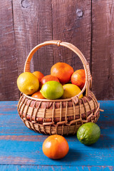 citrus fruits in a basket over wooden background.