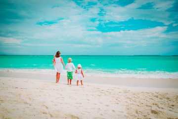 mother with three kids walk on beach