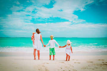 mother with three kids walk on beach