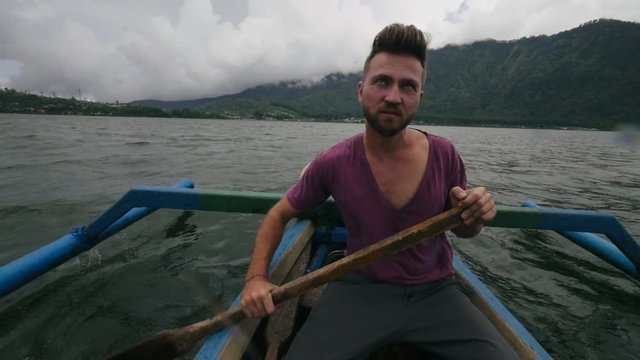 Young caucasian man sailing fishing boat