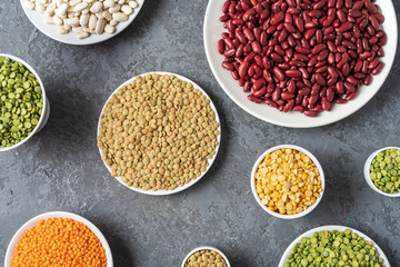 View directly above of assortment of peas, lentils, beans and legumes over gray background.