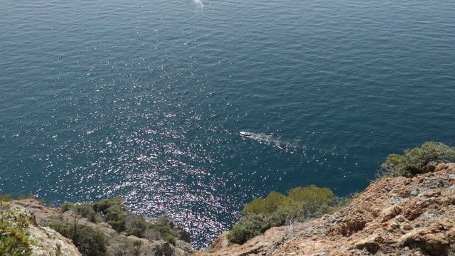 Bonassola, near Cinque Terre, Liguria. A boat in the blue sea seen from an overhanging rock. The promontory called "Salto della Lepre" offers a breathtaking view of the open sea of the Five Lands.