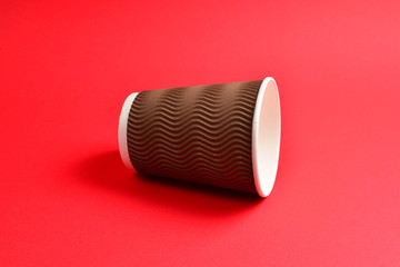 Brown paper cup on a red background. Copy space.