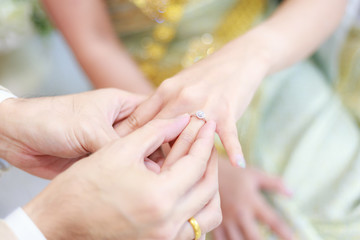 Obraz na płótnie Canvas groom wears ring on bride's finger in wedding ceremony