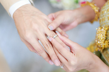 Obraz na płótnie Canvas groom wears ring on bride's finger in wedding ceremony