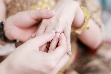 groom wears ring on bride's finger in wedding ceremony