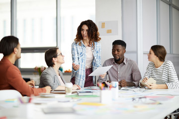 Portrait of contemporary woman talking to multi-ethnic team during meeting in office, copy space