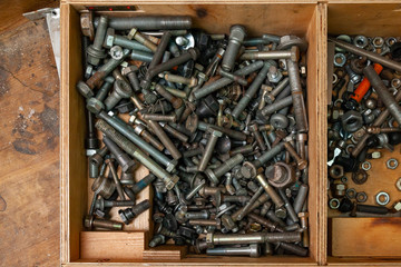 Wooden box with a bunch of nuts, bolts and screws. Tools and fasteners in the workshop.