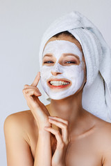 Beautiful young woman applying facial mask on her face. Skin care and treatment, spa, natural...