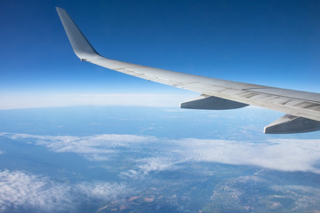 Aircraft wing against blue sky from porthole.