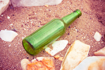 Green bottle of beer abandoned on the beach