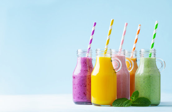 Summer colorful fruit smoothies in jars on blue background. Healthy, detox and diet food concept.