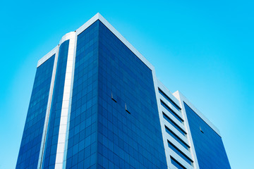 Modern tall business skyscraper with lot of glass windows against blue sky - Image