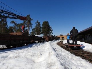 People, a view from the back, riding on a hand trolley, winter, narrow-gauge railway in the forest...