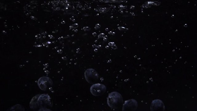Tasty fresh blueberries falling into water. Blue wildberries in slow motion underwater. Food video