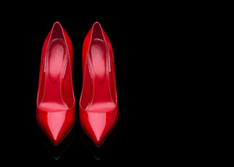 A pair of red women's shoes with high heels. Red shoes on a black background.