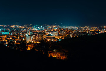 Night view from over capital of Georgia, Tbilisi. Street lights and hills surrounding the city. Blue sky. - Image