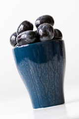 Black grapes without seeds in a blue cup