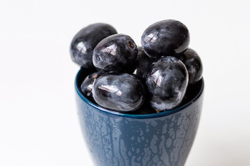 Black grapes without seeds in a blue cup