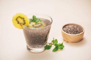 Selective focus of chia seeds drink with water in transparent glass with slice of kiwi