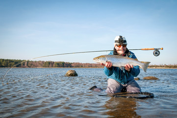 Happy angler with big sea trout on the fly rod