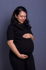 Pregnant mom watching her belly, grey background