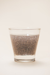 Glass of water with cup of healthy chia seeds and spoon. Text space.