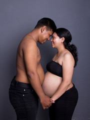 Lovely couple during pregnancy, studio shot on grey background