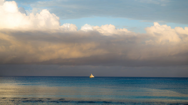 Pastoral sunset landscape of the sea surface with a small sailboat in the Dominican Republic