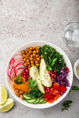  salad with avocado, roasted chickpeas, kale, cucumber, carrot, red cabbage, bell pepper and redish in white bow