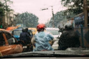 Rain drops on car glass with blur traffic jam on the road in background at Kolkata, India.
