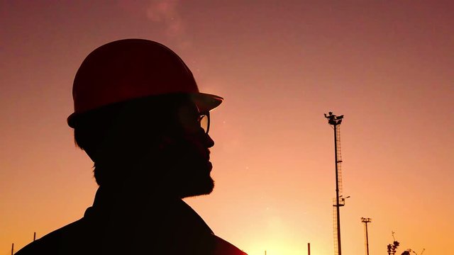 Sagoma di un ingegnere uomo al tramonto che gira la testa a destra. Ripresa in super slowmotion.