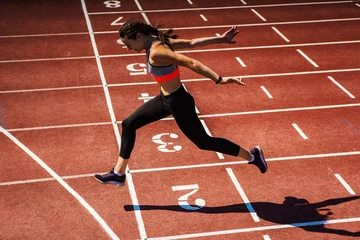Photo sur Plexiglas Best-sellers Sport Vue latérale d& 39 une athlète adolescente en soutien-gorge de sport et collants terminant avec succès la course sur piste au stade