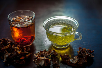 Raw organic amaltas or golden shower tree fruit on wooden surface with its extracted pulp in a glass along with water and green tea in a glass cup.Used for the treatment of worms in intestine.