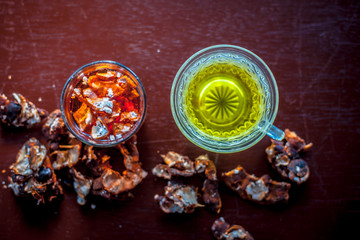 Raw organic amaltas or golden shower tree fruit on wooden surface with its extracted pulp in a glass along with water and green tea in a glass cup.Used for the treatment of worms in intestine.