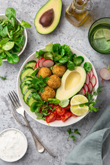 healthy vegan lunch bowl salad with avocado, falafel,cucumber, tomato and redish, top view