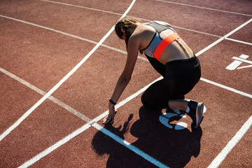 From above back view of teen athlete preparing for sprinting on track in starting position