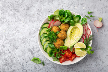 healthy vegan lunch bowl salad with avocado, falafel,cucumber, tomato and redish