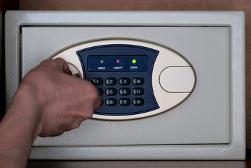 Safe storage of valuables and money in the office and at home. Close-up male hand opens the safe with a combination lock. Safety of things in the Bank Cabinet