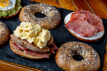 Bagels Selection with cream cheese smoked salmon, eggs and avocados bacon and salmon on rustic wooden background
