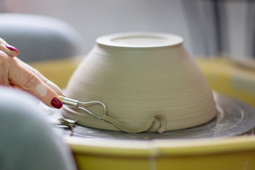 Artist make pot of mug at pottery wheel with hands