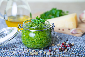 Homemade basil sauce pesto in a glass jar. Close-up, selective focus.