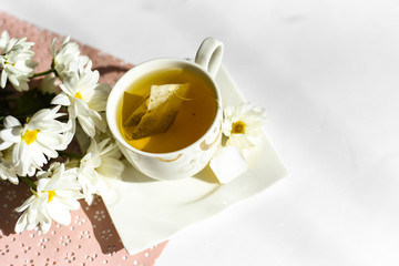 beautiful white chamomile and a cup of green tea on the table