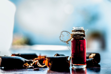 Golden shower tree or garmalo or Amaltas or Cassia fistula oil in a transparent glass bottle along with its fruit and cut pulp on wooden surface.