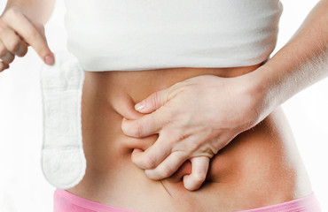 Cropped illness woman in blue dress holding periods calendar for checking menstruation days put hand on abdomen isolated on blue background. Medical, healthcare, gynecological concep