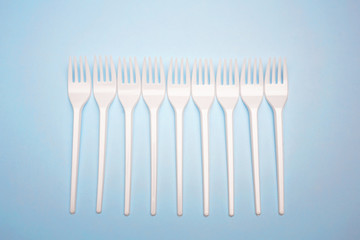 Single-use plastic products: plastic cutlery, cups on bright blue background