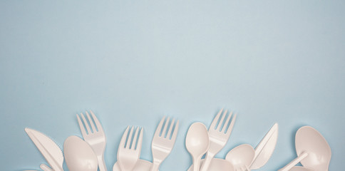 Single-use plastic products: plastic cutlery, cups on bright blue background