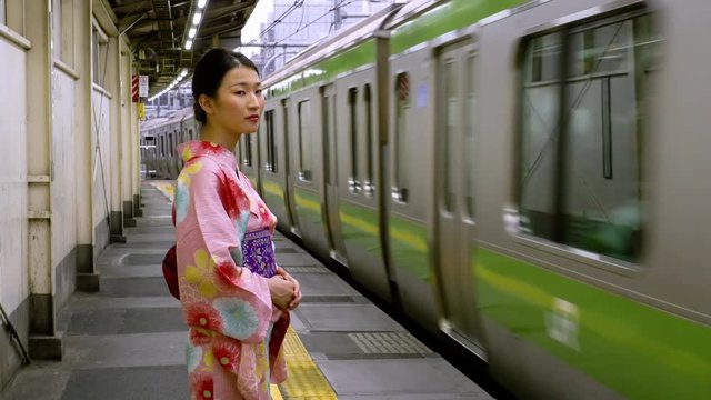 Attractive Japanese woman in a kimono waiting for her train. Tokyo Japan.
