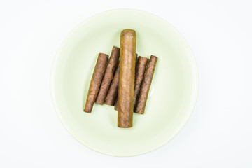 Excellent cigars from twisted sheets on plate with white background.