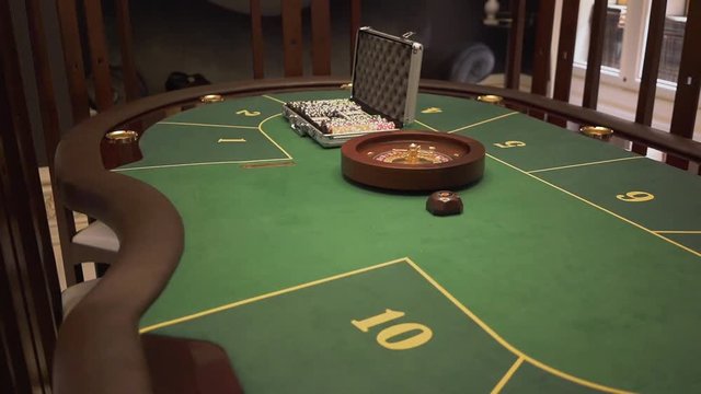 Close up view of the gaming table with green surface with poker set on it in modern casino. Comfortable place with luxury interior waiting for the guests